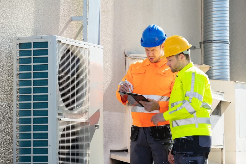 Commercial air conditioning technicians inspecting HVAC unit, discussing maintenance and service solutions for Brooklyn businesses.