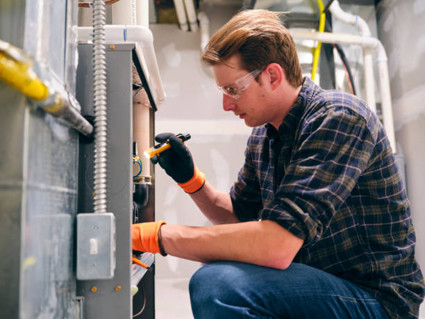 Technician performing furnace repair in commercial setting, focused on diagnostics and maintenance, wearing safety gloves and goggles.