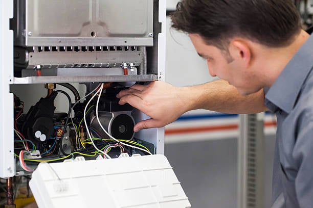 HVAC technician inspecting and repairing a furnace, highlighting expertise in commercial furnace installation and maintenance for reliable heating in Brooklyn, NY.